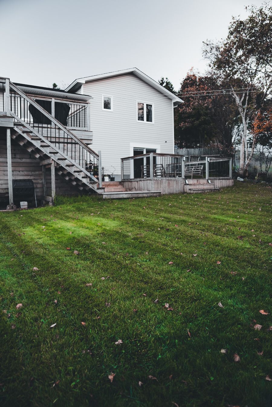 House with a timber deck overlooking a maintained lawn